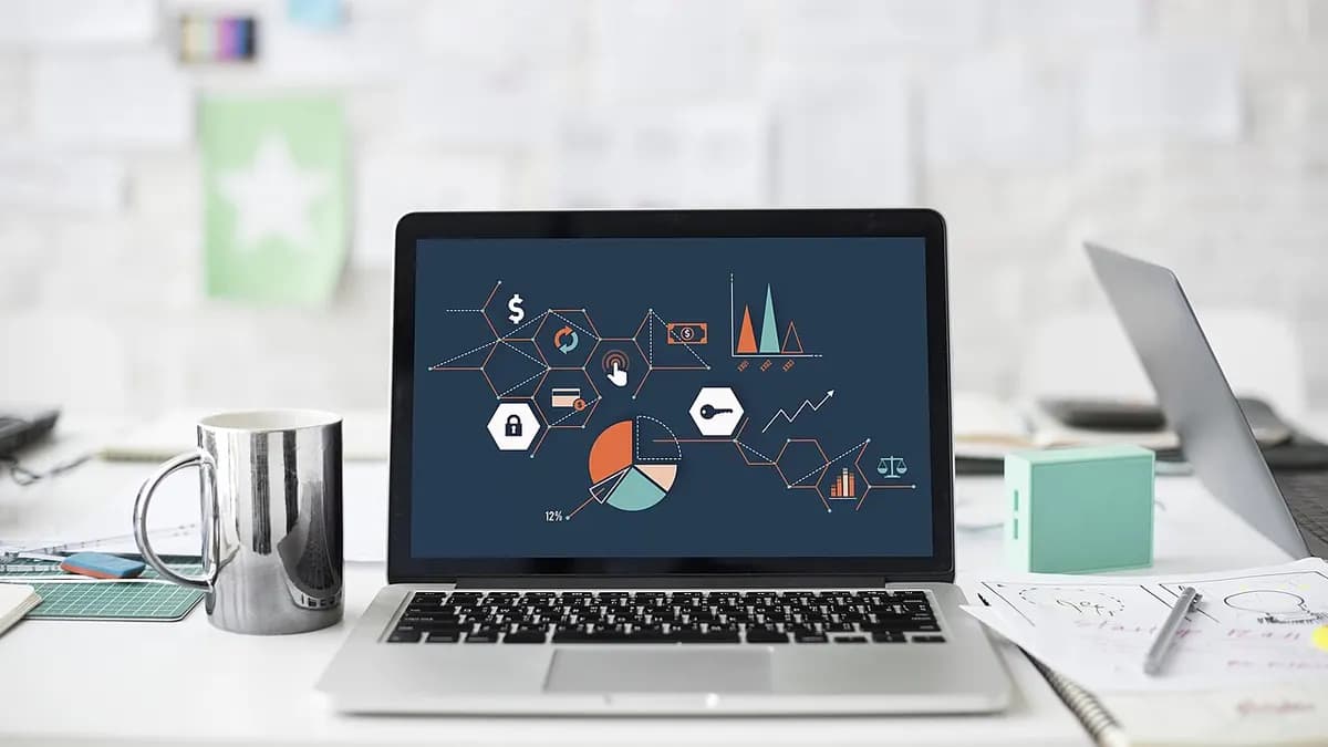 Laptop on a desk showing charts and metrics on its screen